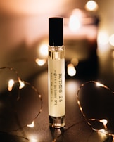 A perfume bottle labeled 'Nutmeg 26 MORRA Autumn No.2 eau de parfum' stands upright on a dark surface. Soft, warm lighting surrounds the bottle, creating a cozy and intimate atmosphere. Small, fairy lights are elegantly arranged around the bottle, adding a touch of sparkle and enhancing the ambient glow.