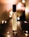 A perfume bottle labeled 'Nutmeg 26 MORRA Autumn No.2 eau de parfum' stands upright on a dark surface. Soft, warm lighting surrounds the bottle, creating a cozy and intimate atmosphere. Small, fairy lights are elegantly arranged around the bottle, adding a touch of sparkle and enhancing the ambient glow.