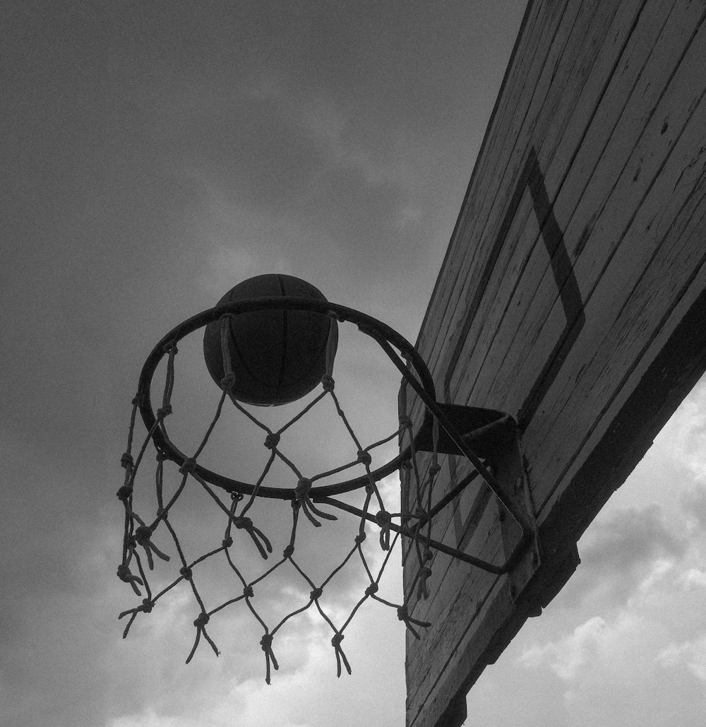 basketball hoop under cloudy sky in grayscale photography