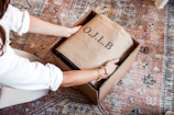 Hands opening a box with o.j.l.b. branding