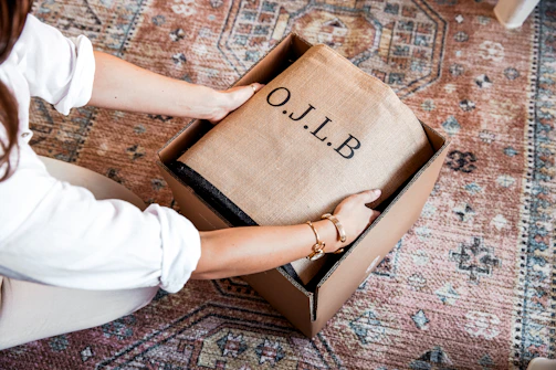Hands opening a box with o.j.l.b. branding