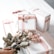 A collection of elegantly wrapped gift boxes in white with pink ribbons, arranged on a white surface. In the foreground, a hand is holding a bouquet of pink roses, complementing the color scheme of the gift boxes.