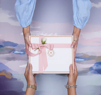 Two hands exchanging a beautifully wrapped gift box.