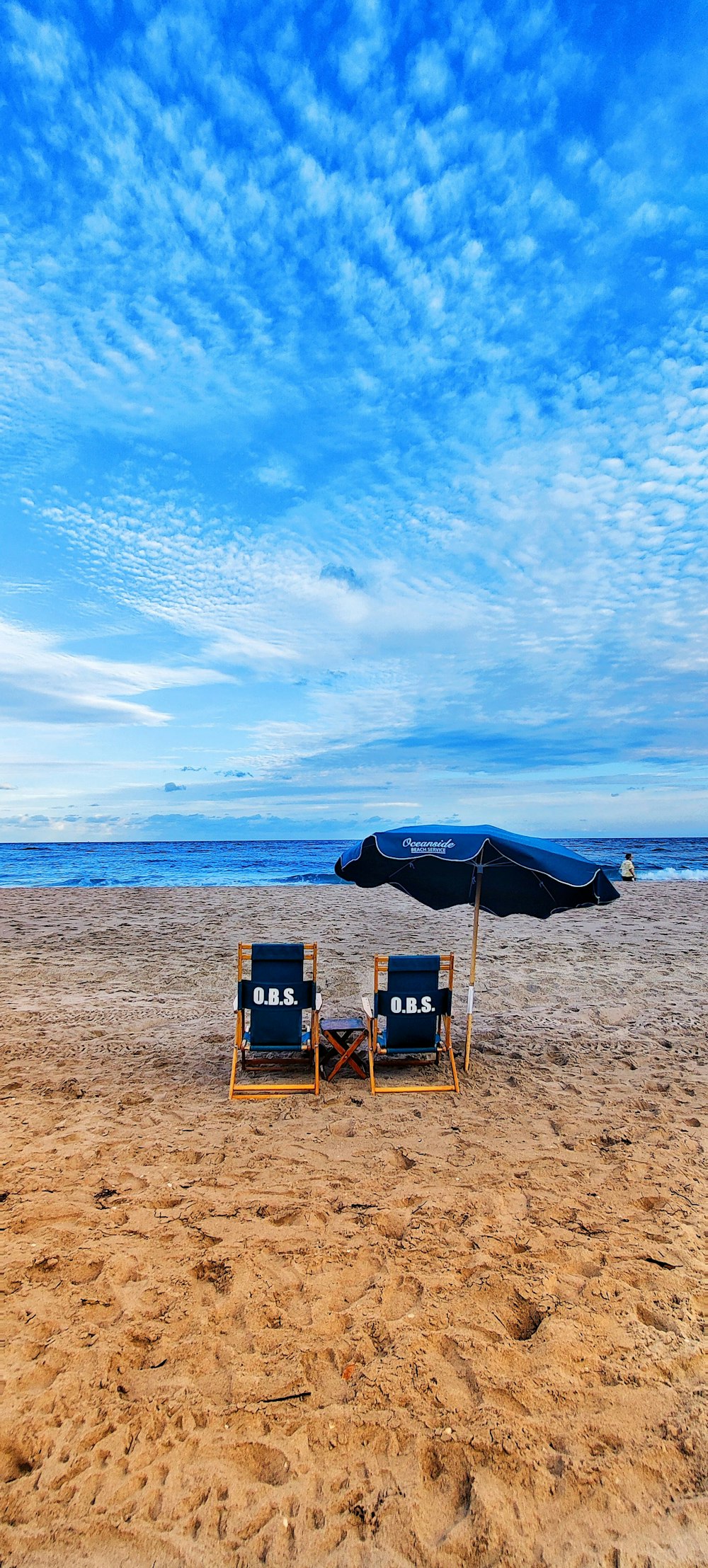 chaises pliantes en bois marron sur le sable brun près de la mer sous le ciel bleu pendant la journée