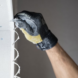 a person with a black glove is painting a wall