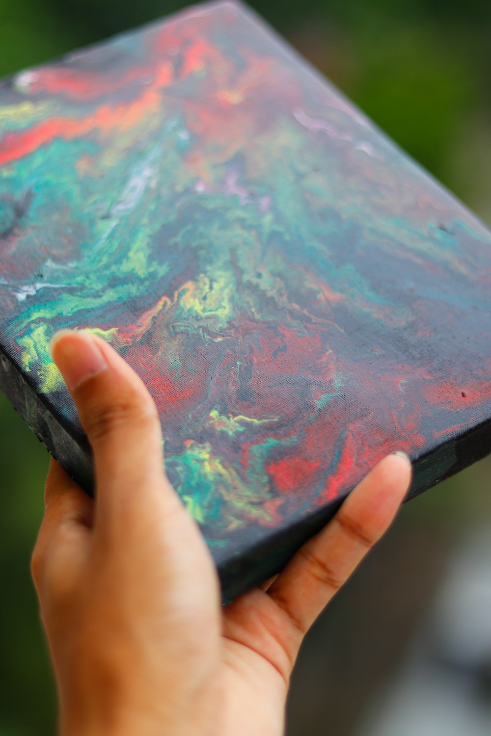 person holding blue green and pink abstract painting