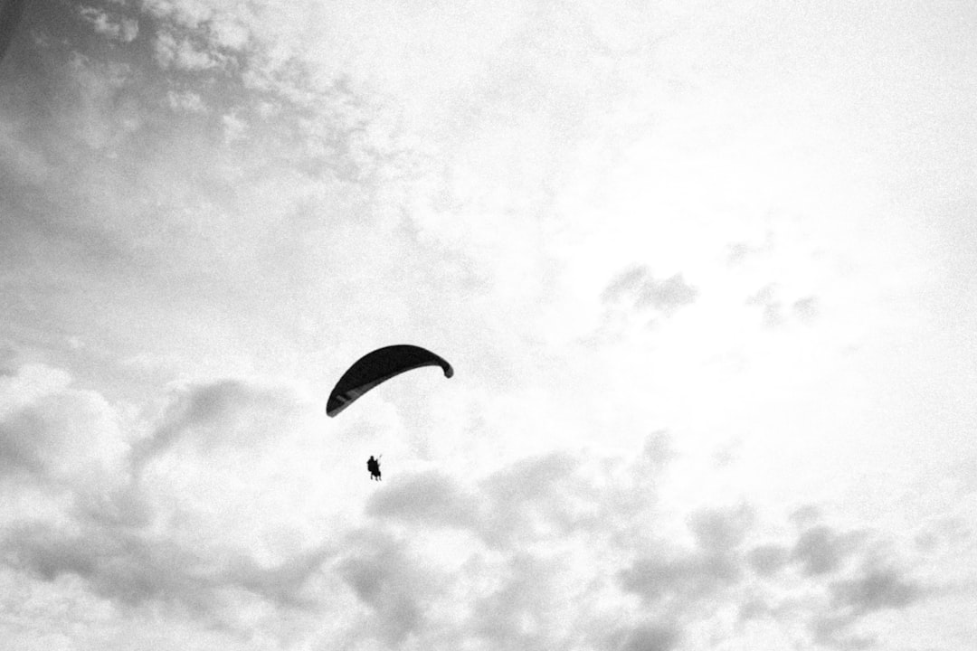 grayscale photo of person riding parachute
