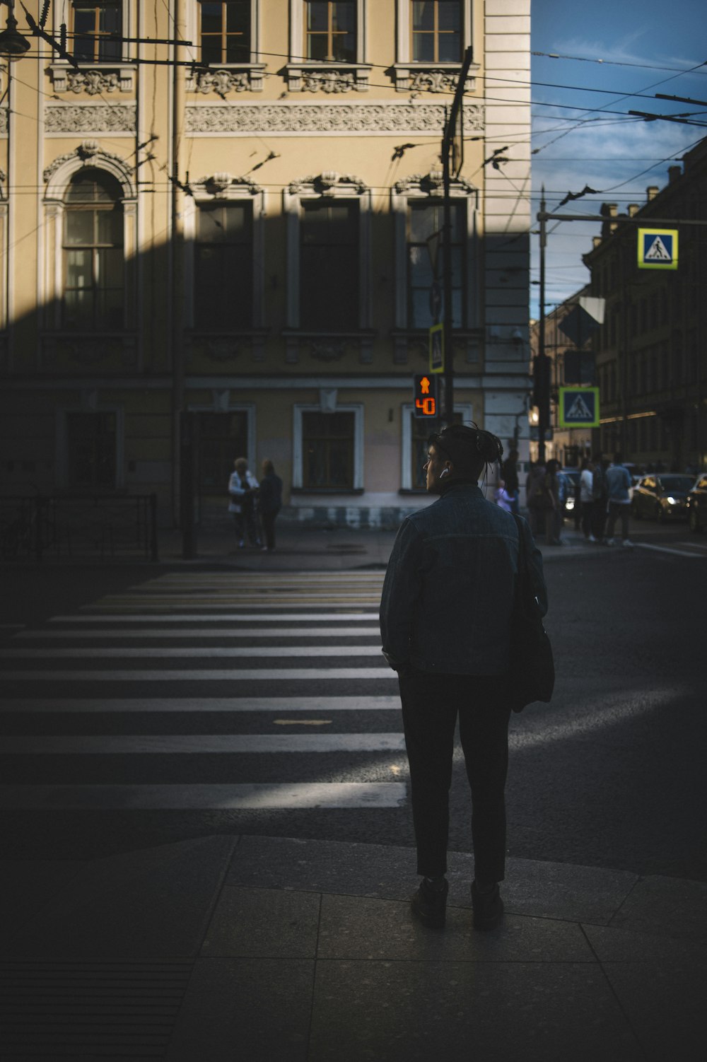 man in white jacket and black pants standing on pedestrian lane during daytime