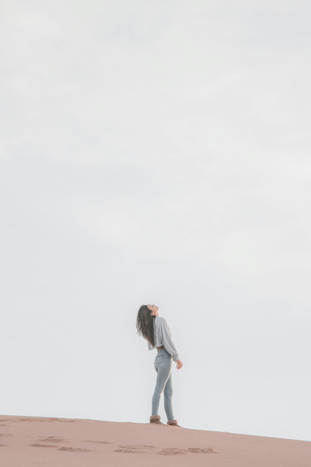 woman in white long sleeve shirt and gray pants standing on white snow covered ground during