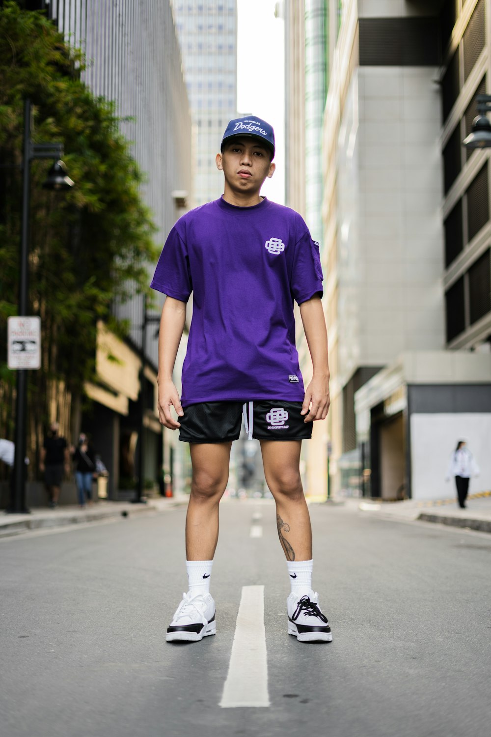 man in blue crew neck t-shirt and black shorts standing on road during daytime