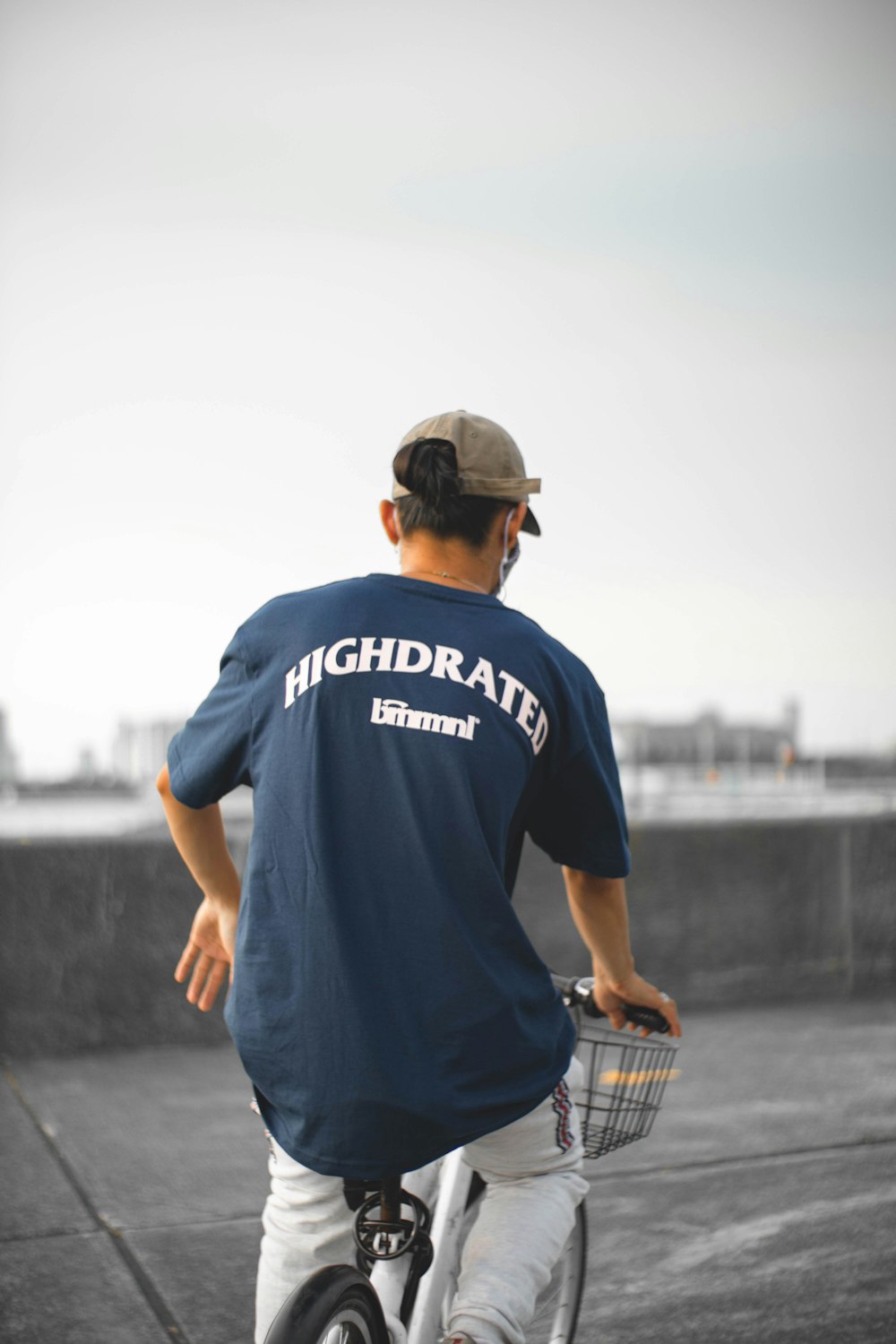 man in blue crew neck t-shirt and black cap standing on gray concrete pavement during