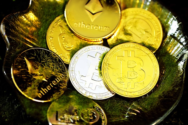 A collection of shiny cryptocurrency coins, including Bitcoin, Ethereum, and others, resting on a bed of green moss inside a transparent dish. The coins are gold and silver, reflecting light and creating a bright, luxurious appearance.