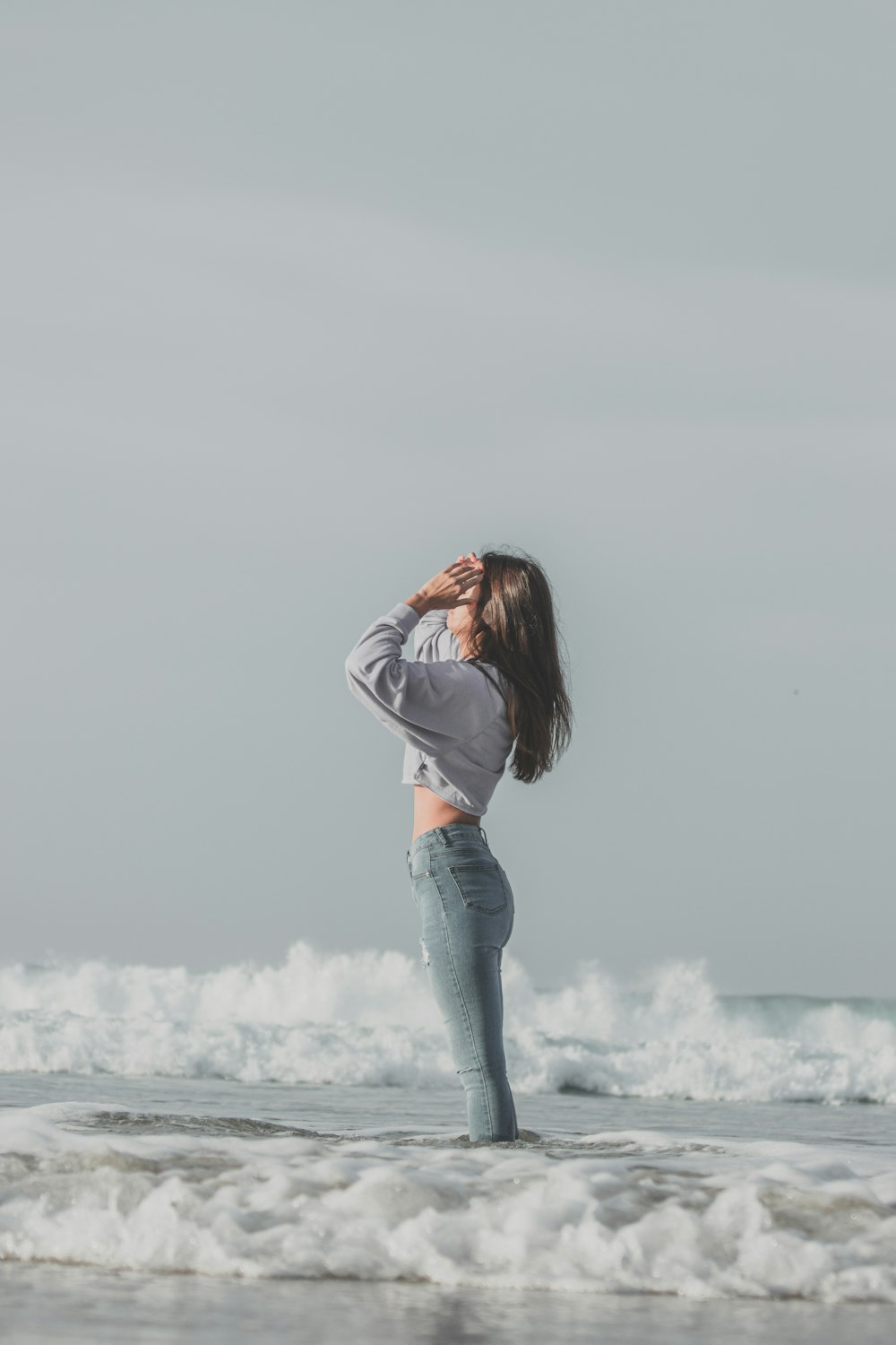 woman in gray long sleeve shirt and blue denim jeans standing on white snow covered ground