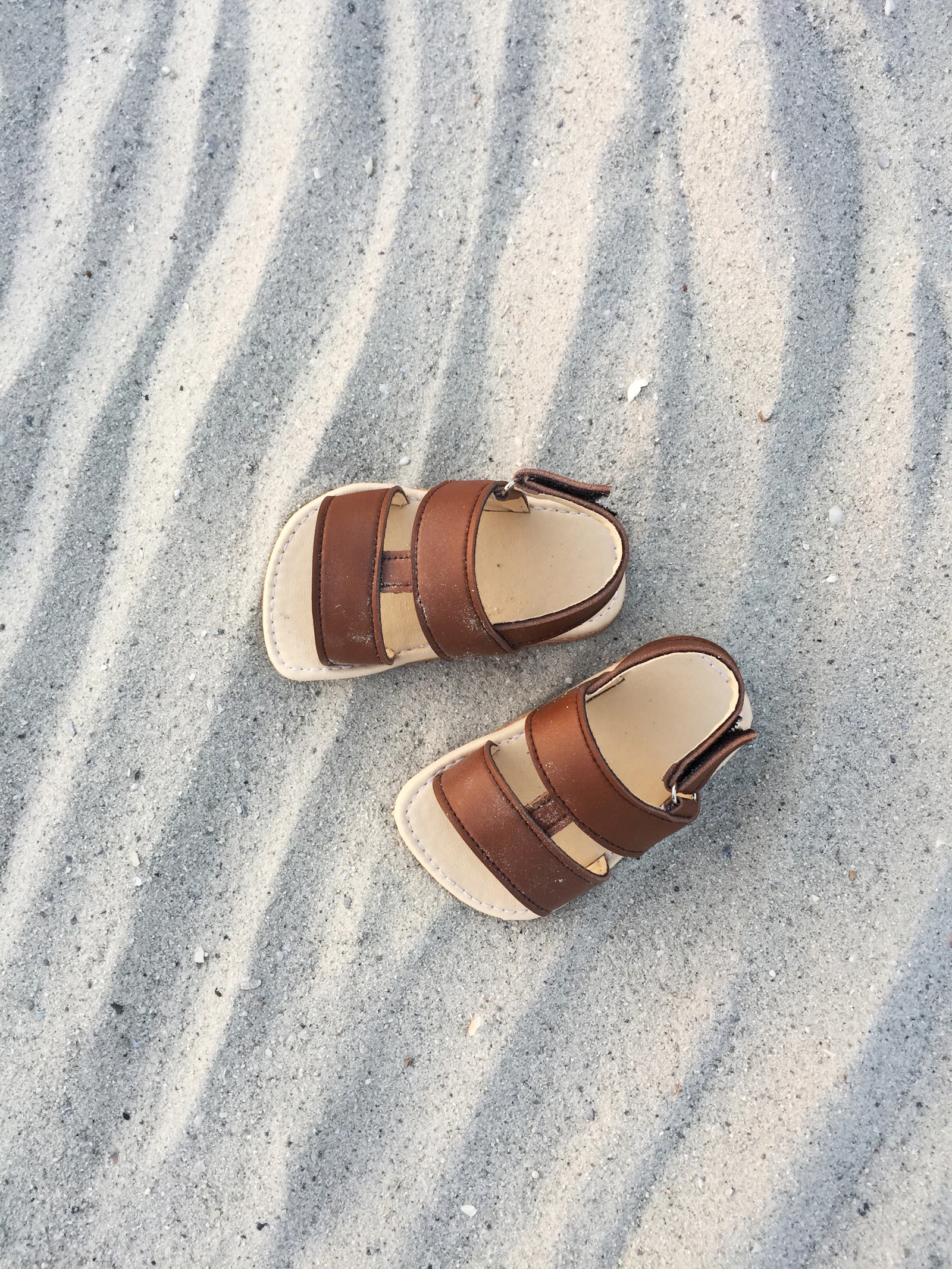Pair of leather sandals resting on the sand