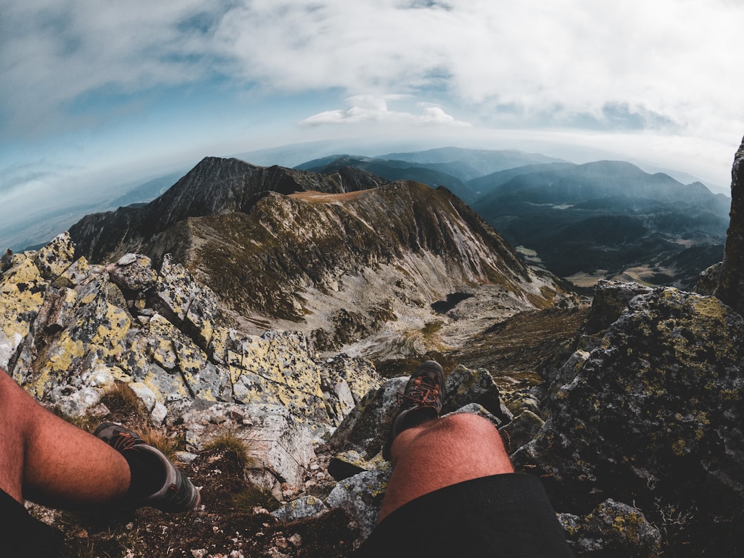 person in black shorts sitting on rocky mountain during daytime