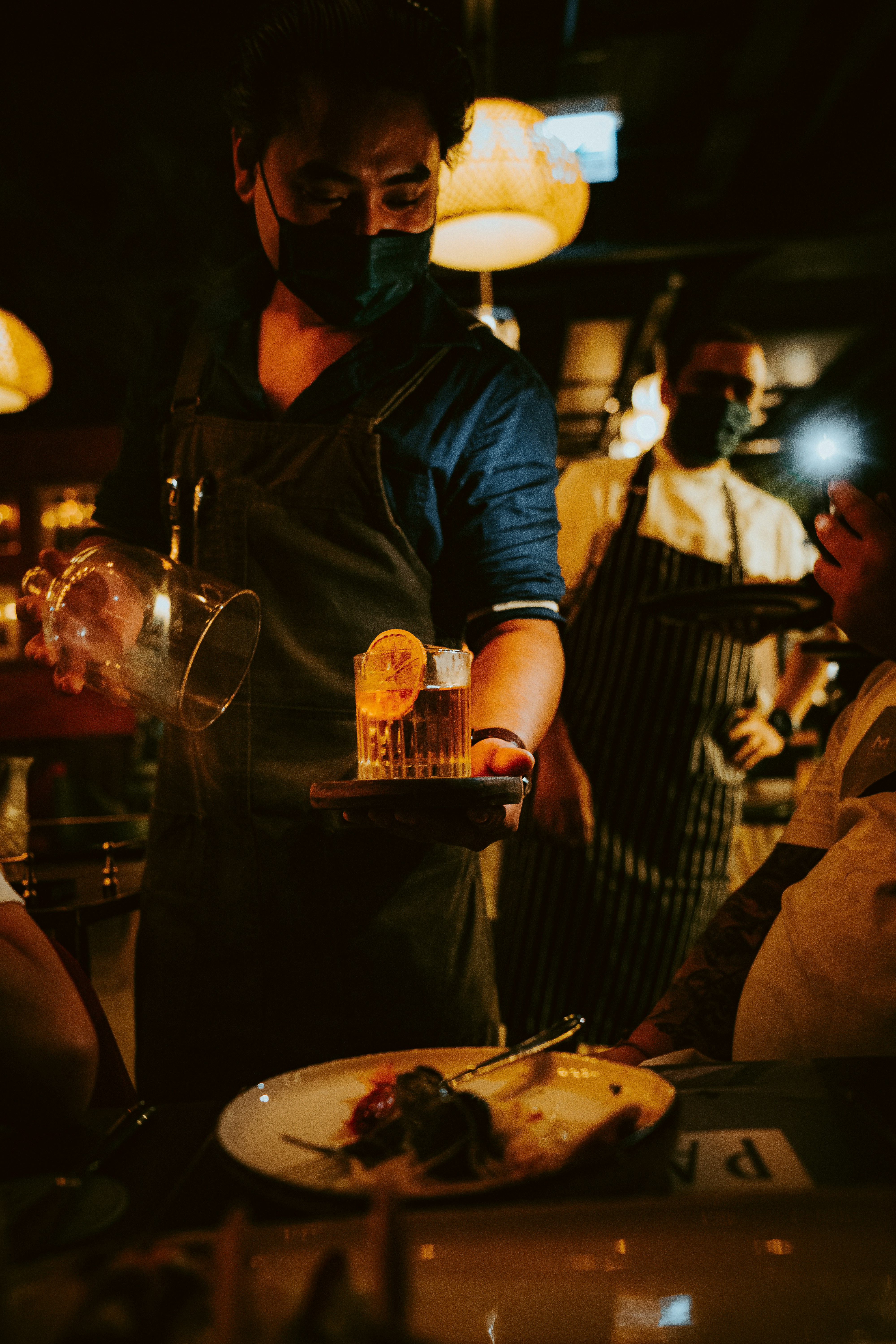 uomo in giacca di pelle nera che tiene una tazza di vetro trasparente