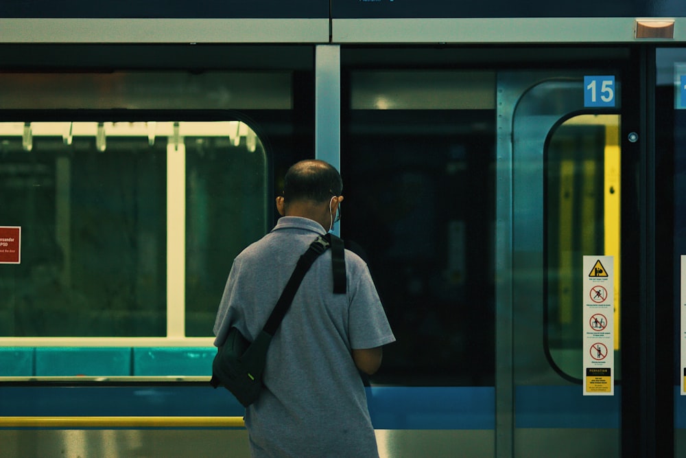 man in blue dress shirt standing in front of train