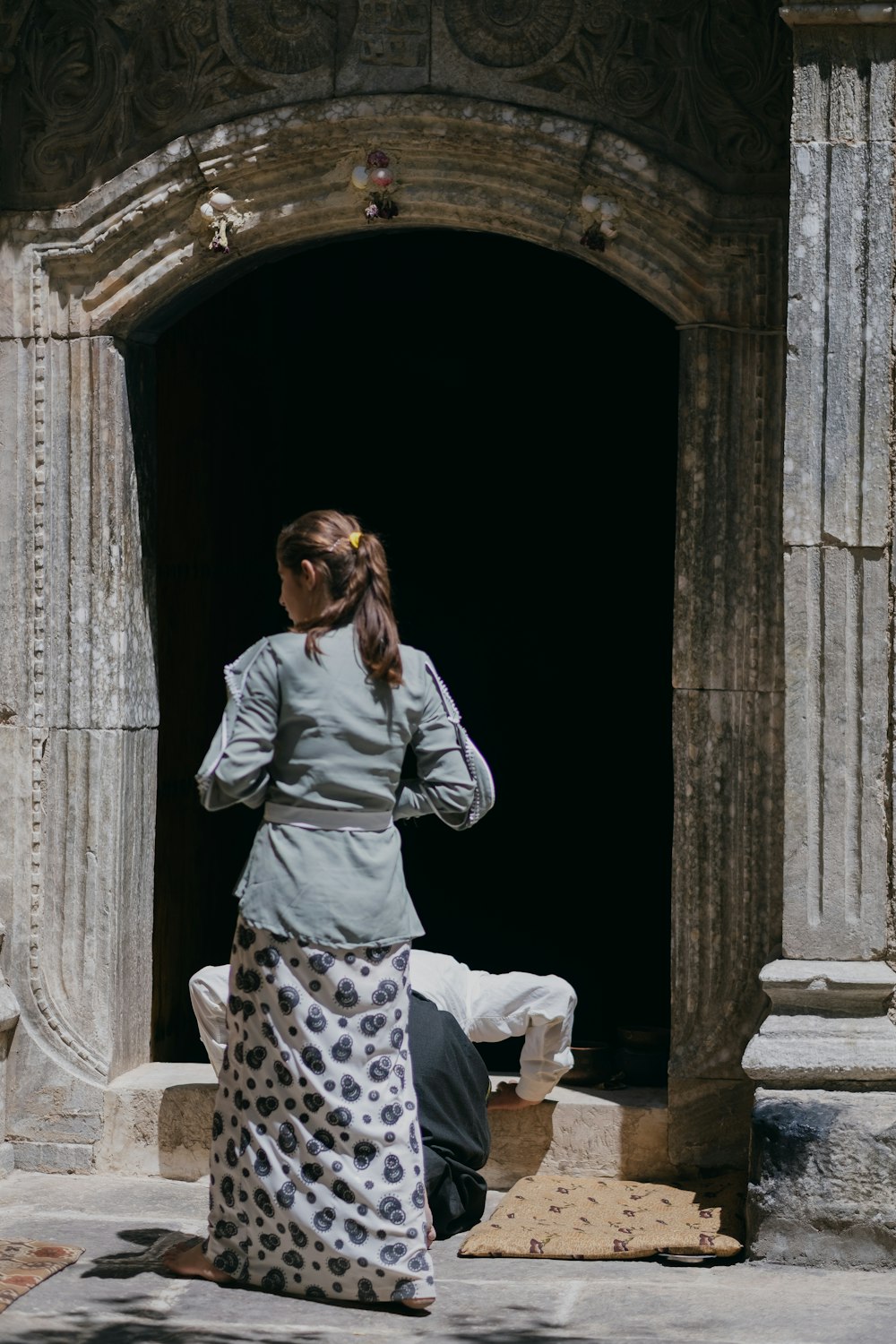 woman in gray long sleeve shirt and black and white pants sitting on white and black