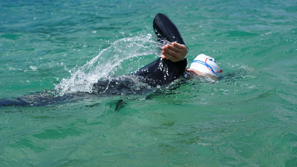 person in white and blue cap and black and white wet suit in water