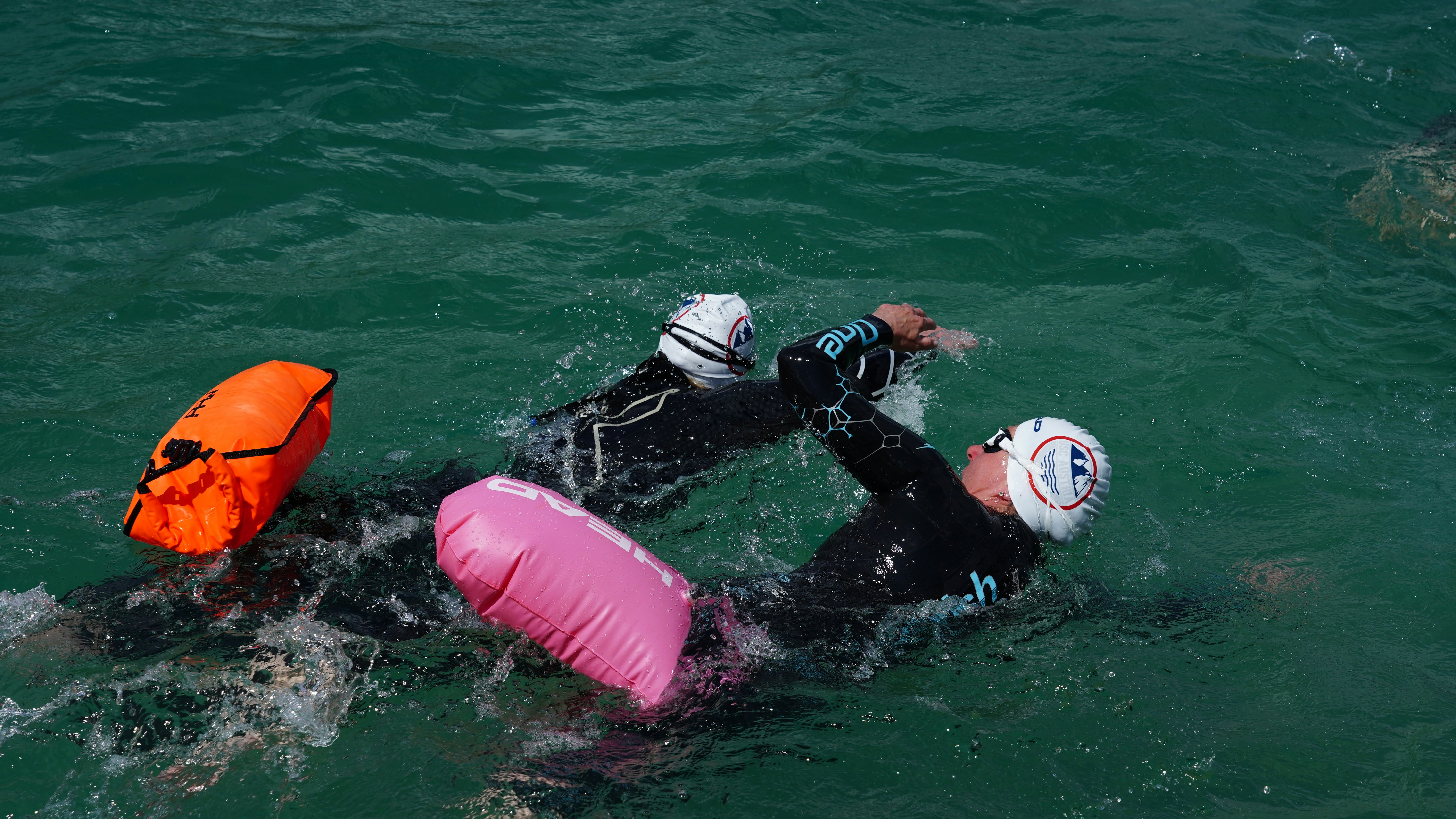 2 persone in muta bianca e nera su galleggiante gonfiabile rosa