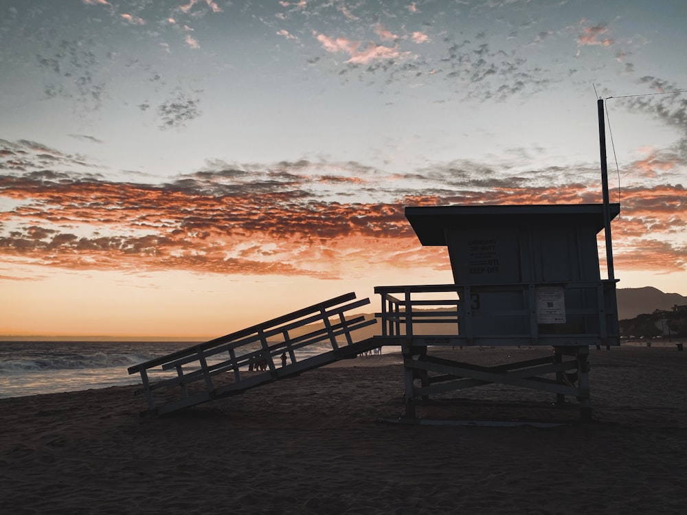 brown wooden lifeguard house on beach during sunset