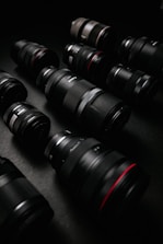 Close-up of a variety of camera lenses arranged on a textured surface.