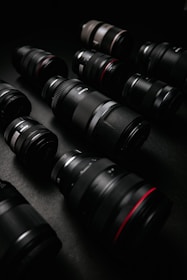 Close-up of a variety of camera lenses arranged on a textured surface.