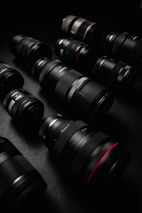 A collection of prime and zoom lenses arranged on a black reflective surface.