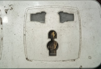 Close-up of electrician repairing a wall socket with care