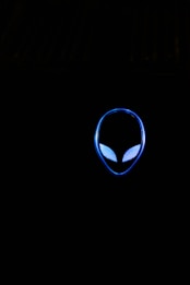 A glowing blue alien head silhouette with distinct eyes is set against a completely dark background. The design is minimalist and emphasizes sleek lines and vivid blue lighting.