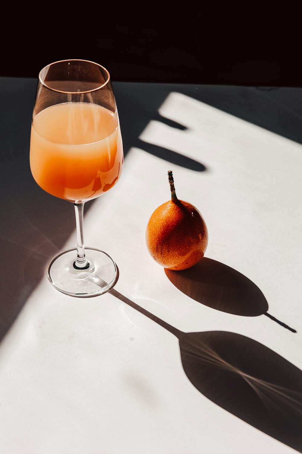 銀のスプーンの横の透明なワイングラスに入ったオレンジジュース