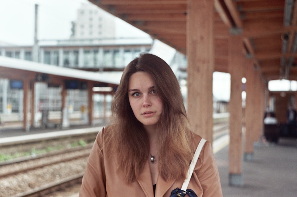 woman in brown leather jacket standing on train rail during daytime