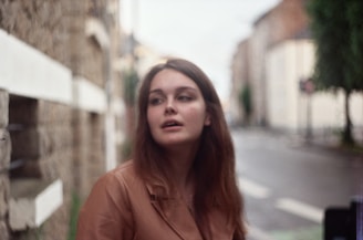 woman in orange long sleeve shirt standing on road during daytime