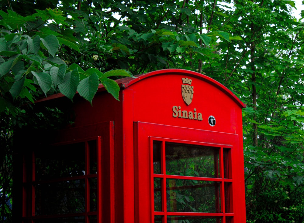 red telephone booth beside green leaves