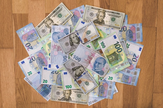 A close-up of various international banknotes spread out on a wooden table.