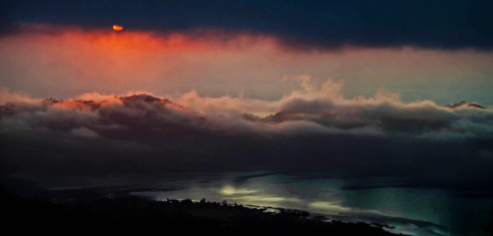 silhouette of mountain under orange and gray clouds