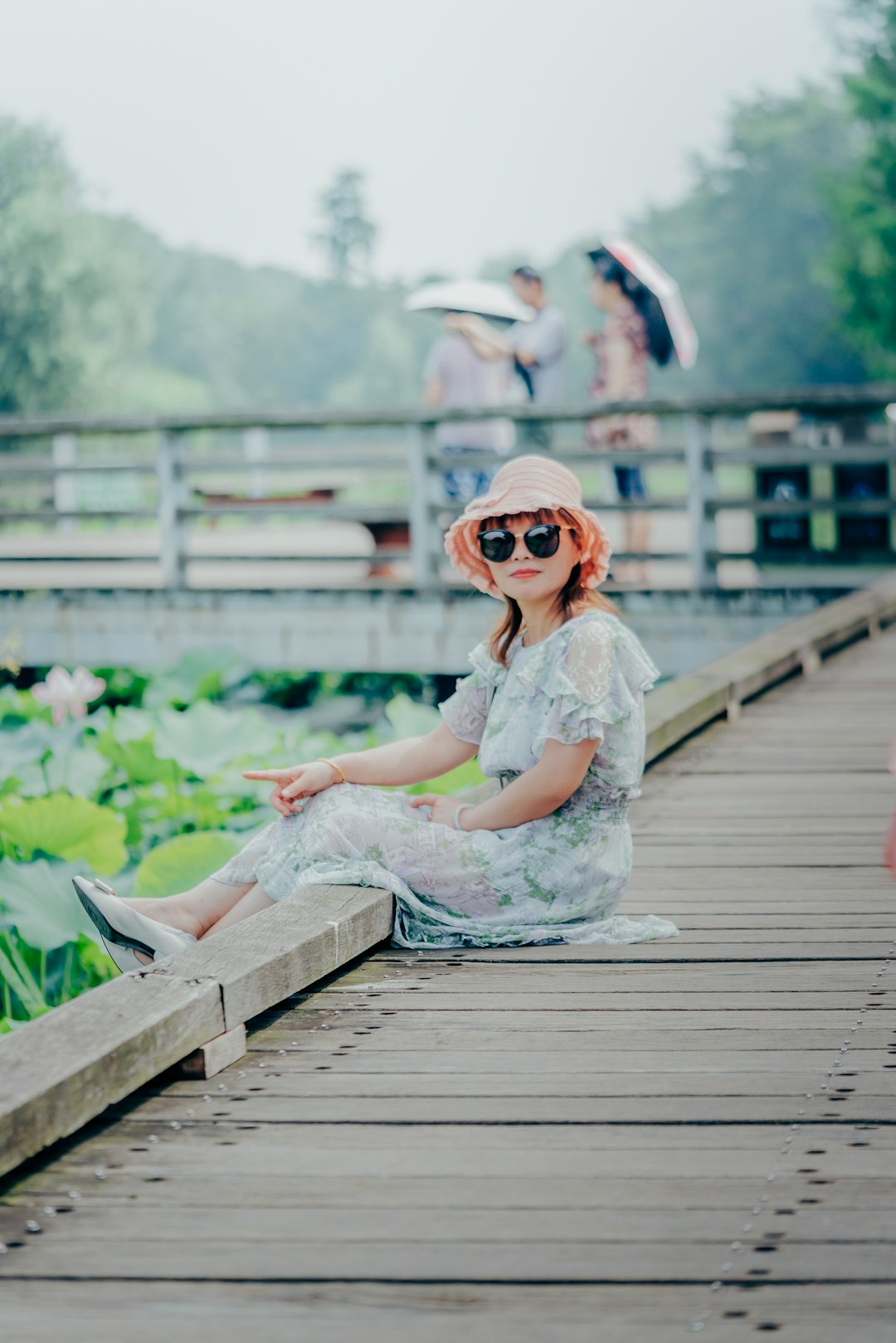 woman in white floral dress sitting on brown wooden dock during daytime