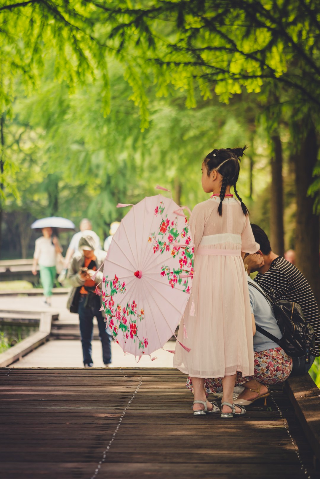 woman in white dress holding umbrella walking on sidewalk during daytime