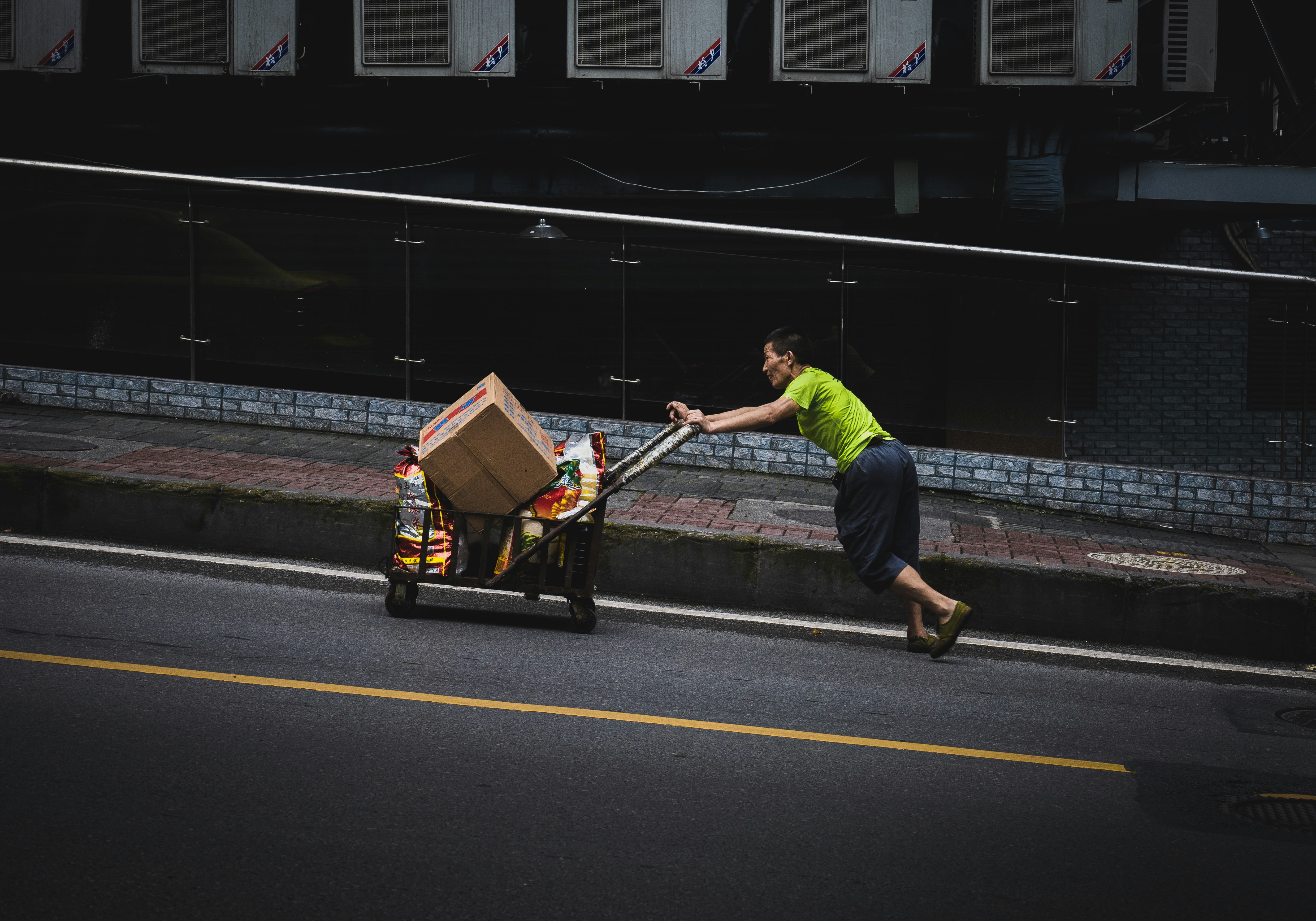 man in green t-shirt and black pants holding brown cardboard box