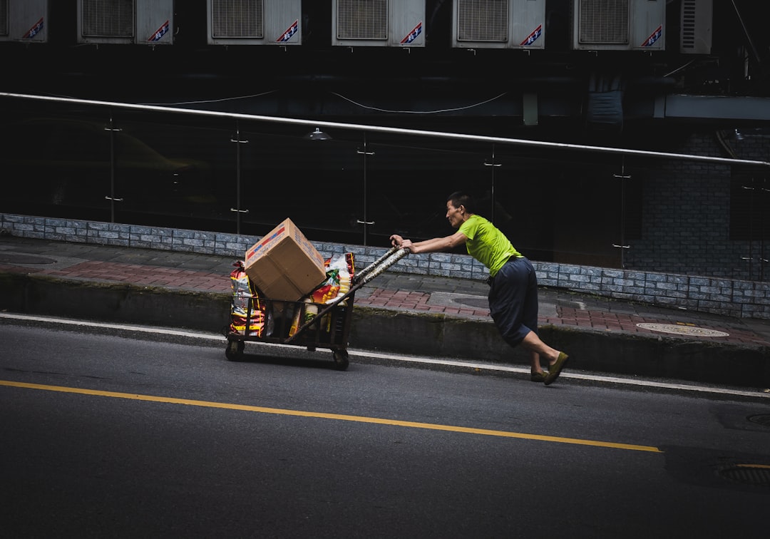 man in green t-shirt and black pants holding brown cardboard box