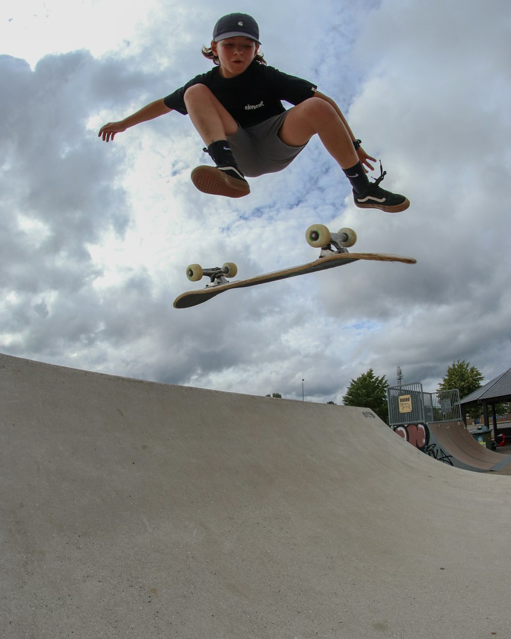 man in black t-shirt and black shorts doing skateboard stunts during daytime