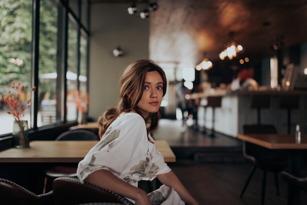 woman in white shirt sitting on brown leather chair