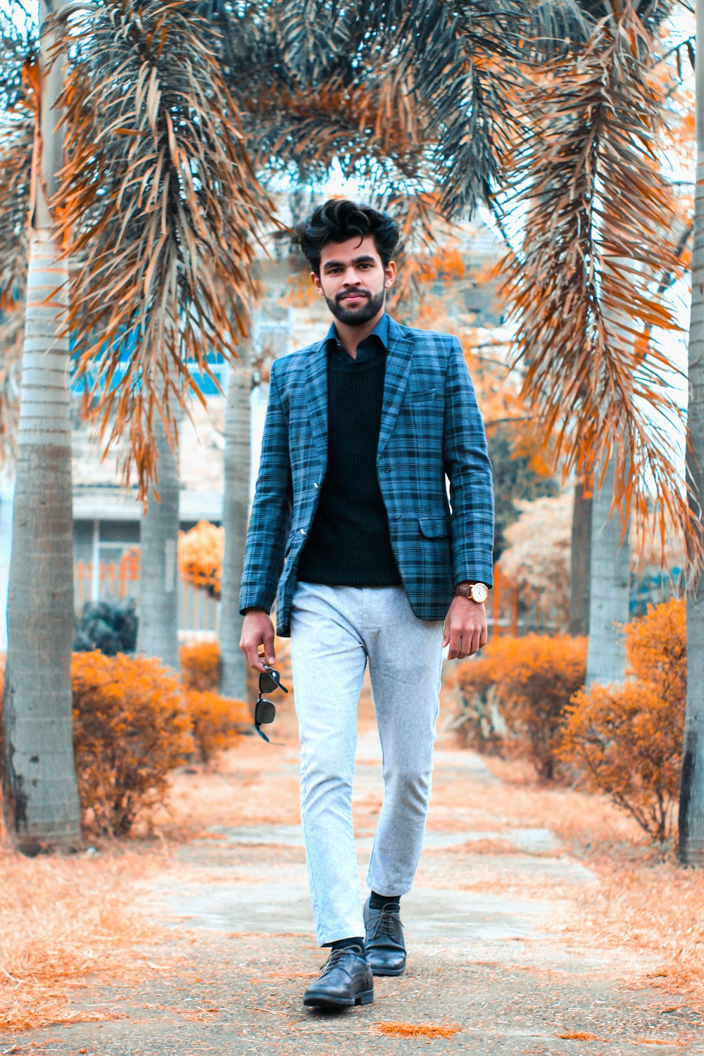 man in blue jacket standing near palm tree during daytime