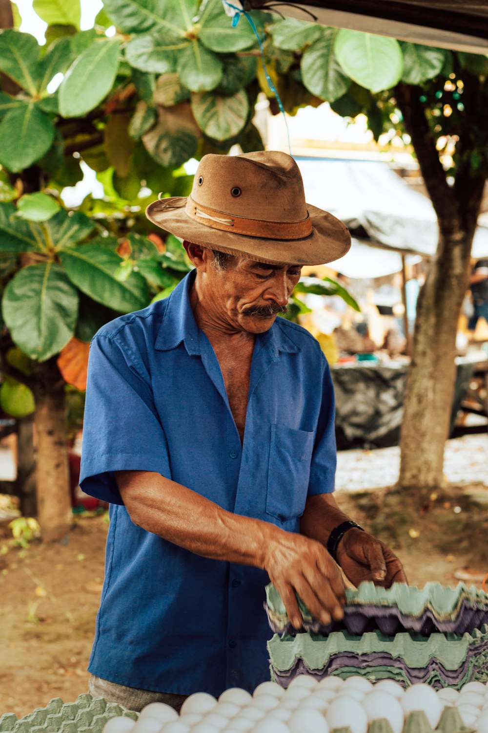 man in blue button up shirt wearing brown fedora hat