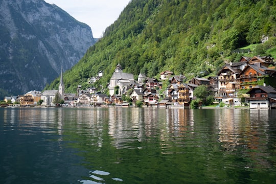houses near green mountain and body of water during daytime in Hallstatt Austria Austria