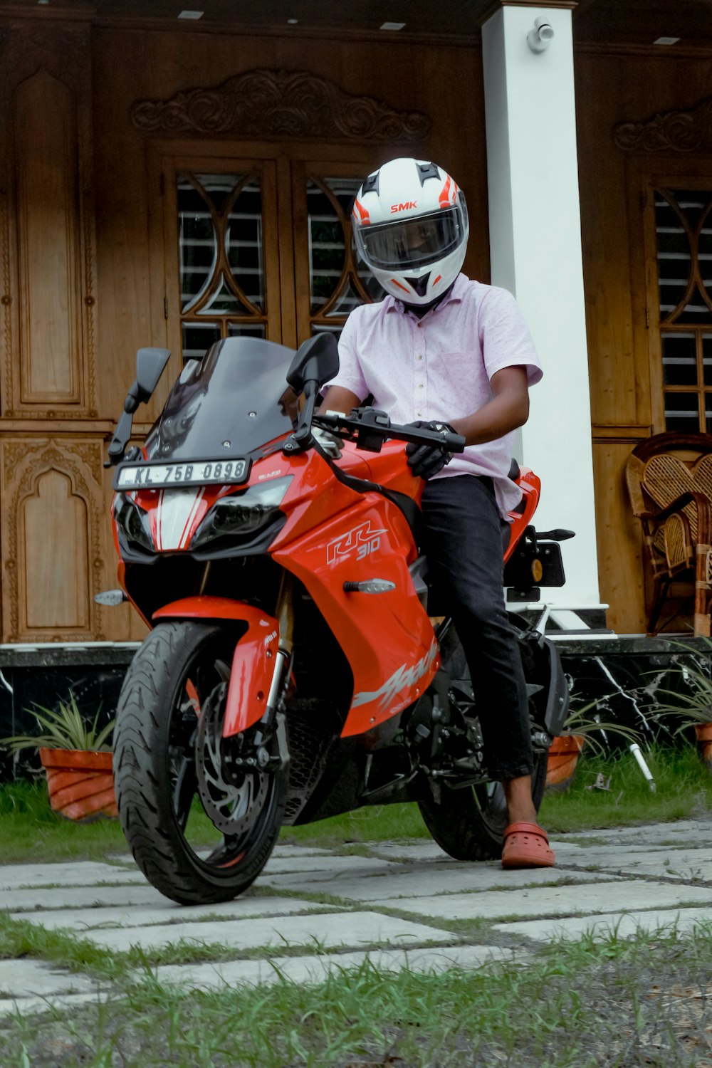 man in white t-shirt and orange helmet riding orange and black sports bike