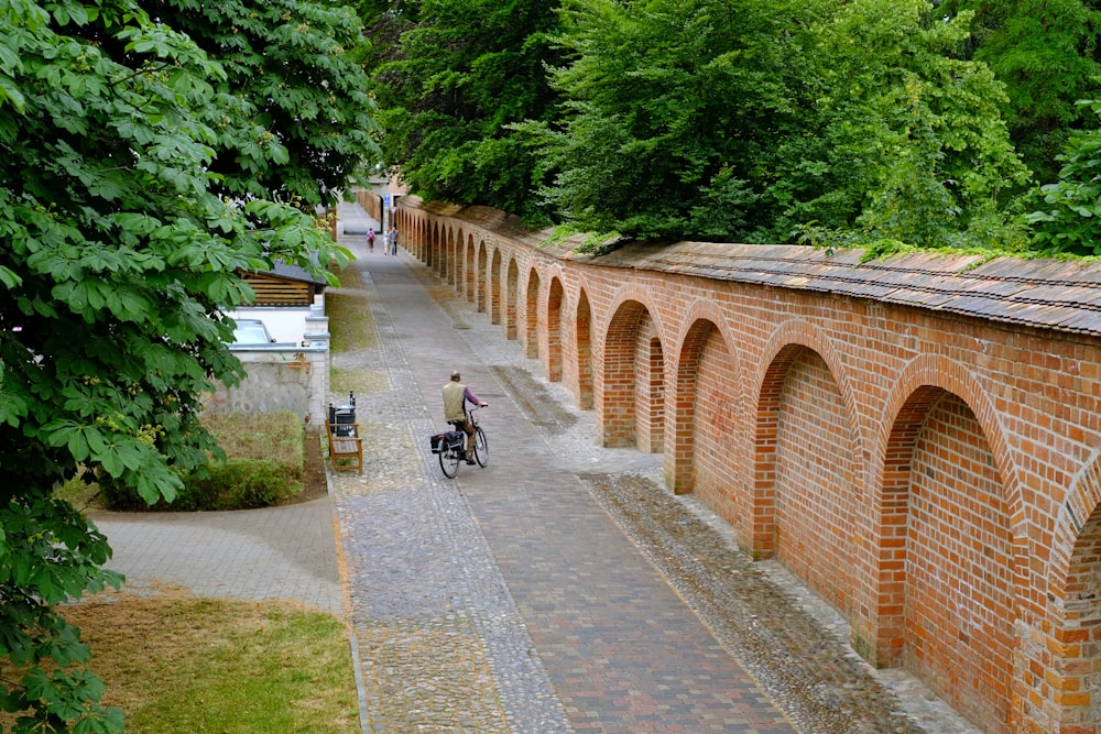 man in black jacket riding bicycle on gray concrete bridge during daytime