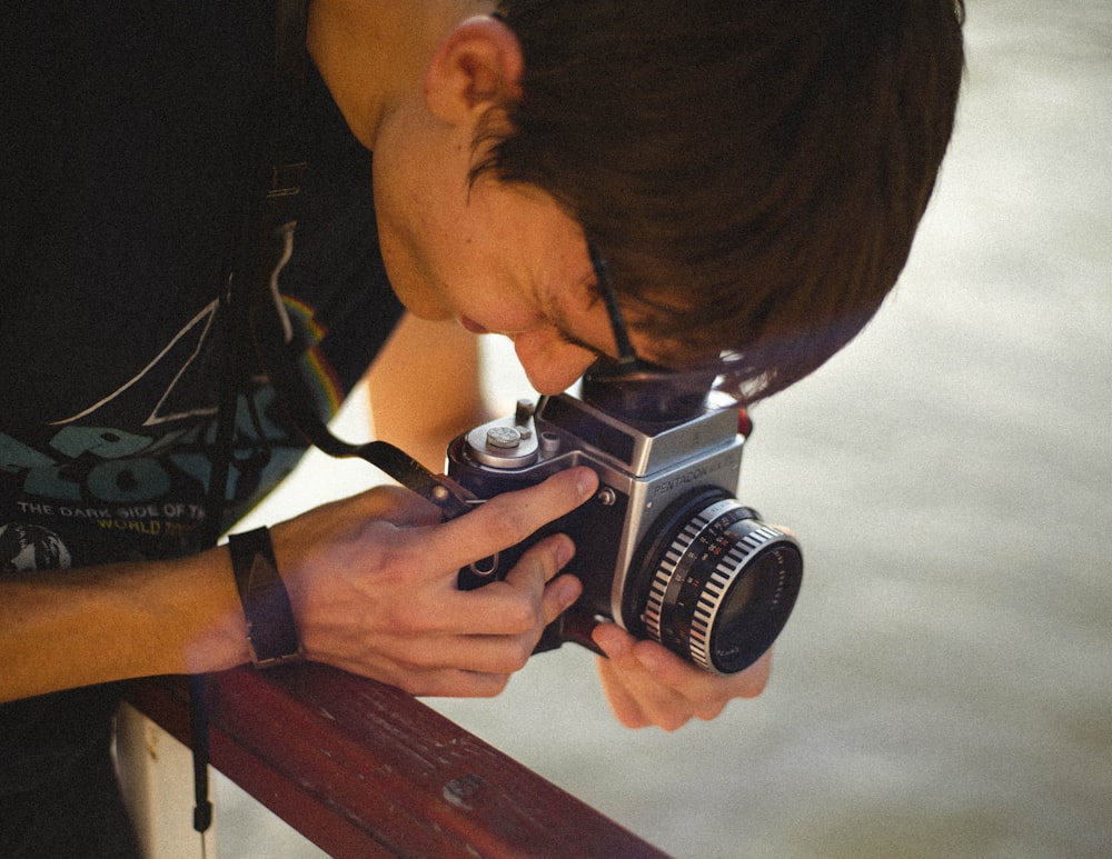 man in black and white shirt holding black and silver dslr camera