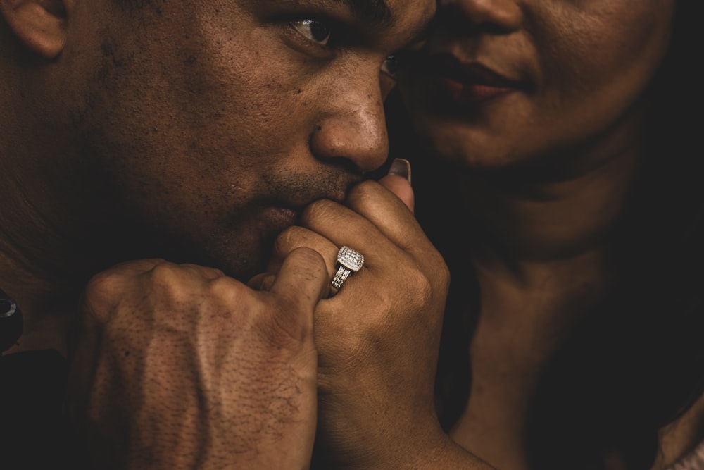 man wearing silver ring holding his face