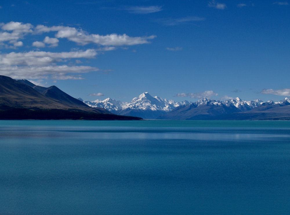 corpo d'acqua blu vicino alla montagna sotto il cielo blu durante il giorno